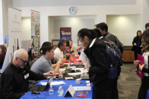 people talking at a table, sitting on one side and standing on the other side